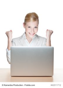 Smiling young businesswoman sitting at a desk with laptop