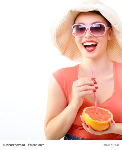 Beautiful pinup girl drinking juice of grapefruit in sunglssses